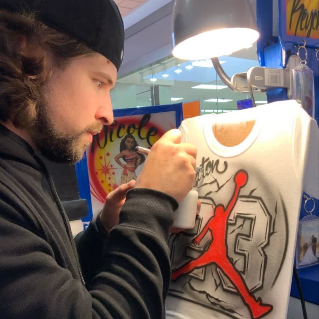 Kreations artist airbrushing a custom jersey in the shop